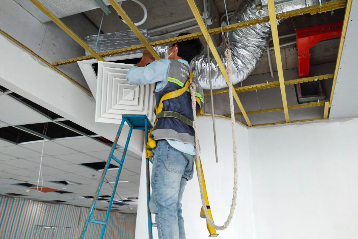 Kỹ thuật viên LU Design thi công lắp đặt và định vị hệ thống ống gió làm mát âm trần tại công trình