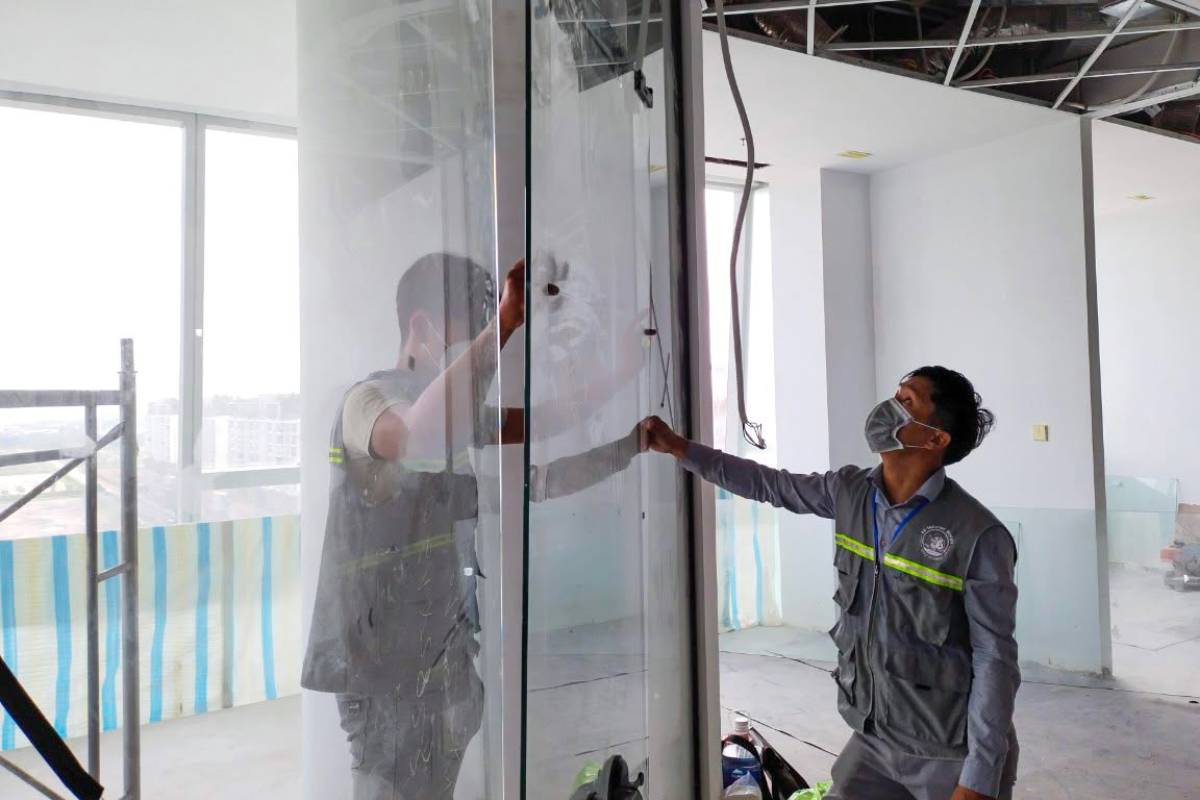 Kỹ sư giám sát trực tiếp kiểm tra độ chuẩn xác của vách kính cường lực phân chia không gian làm việc 