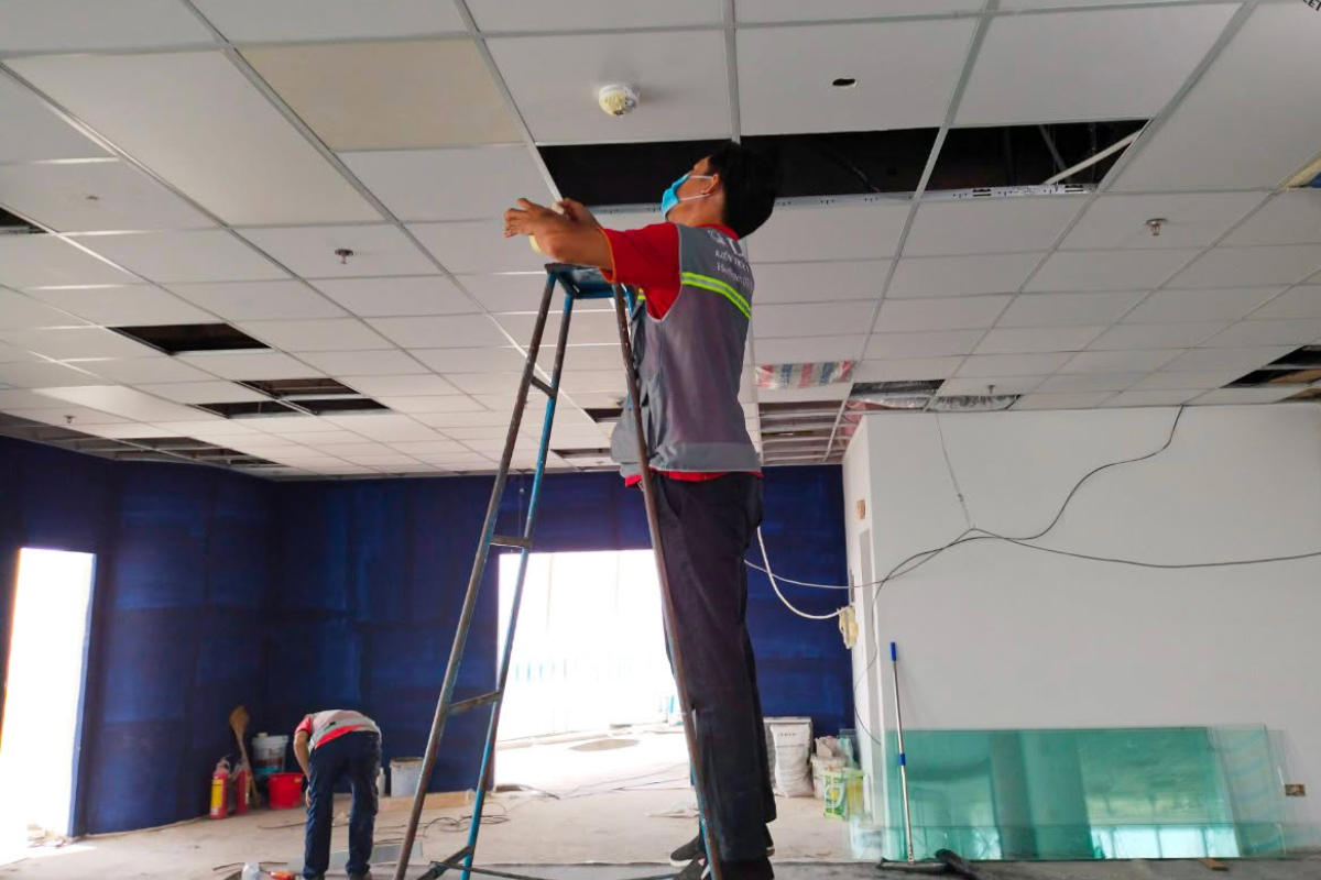 Kỹ thuật viên LU Design điều chỉnh thiết bị cảm biến và hệ thống kỹ thuật âm trần trước khi đóng nắp trần thả
