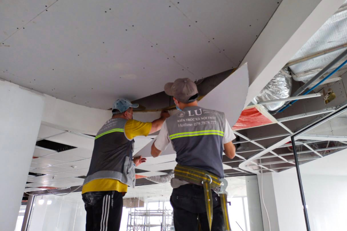 Đội ngũ thi công LU Design tập trung lắp đặt tấm thạch cao uốn cong định hình dầm trần trang trí để kịp tiến độ bàn giao dự án